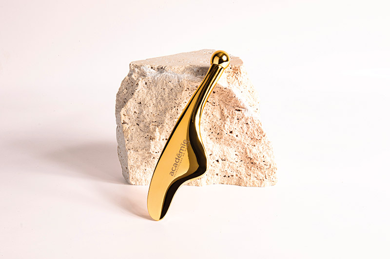 Le Gua Sha XL signé Académie Scientifique de Beauté se pare d’un voile doré, alliant élégance et raffinement. Son design précieux, associé à une technicité avancée, sublime le geste de la praticienne et renforce son expertise.